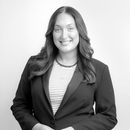 Professional headshot of a smiling woman in a black blazer and striped top, facing the camera.
