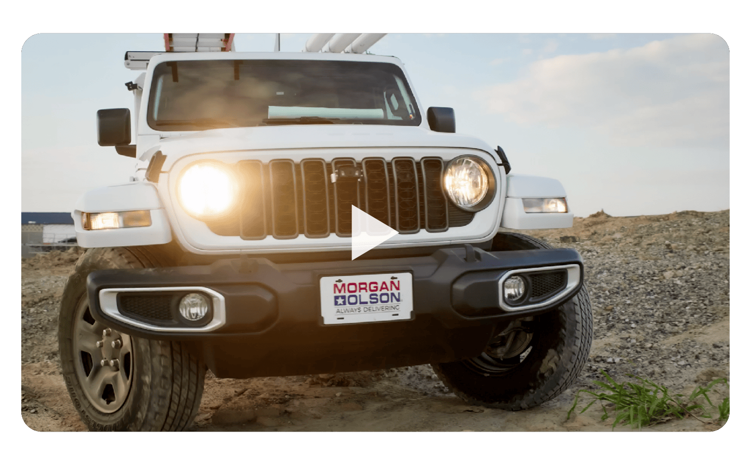 Video thumbnail: front view of a white off-road SUV on rocky terrain with a centered play button overlay