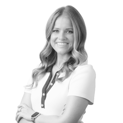 Smiling woman with long wavy hair wearing a white blouse, arms crossed in a professional headshot