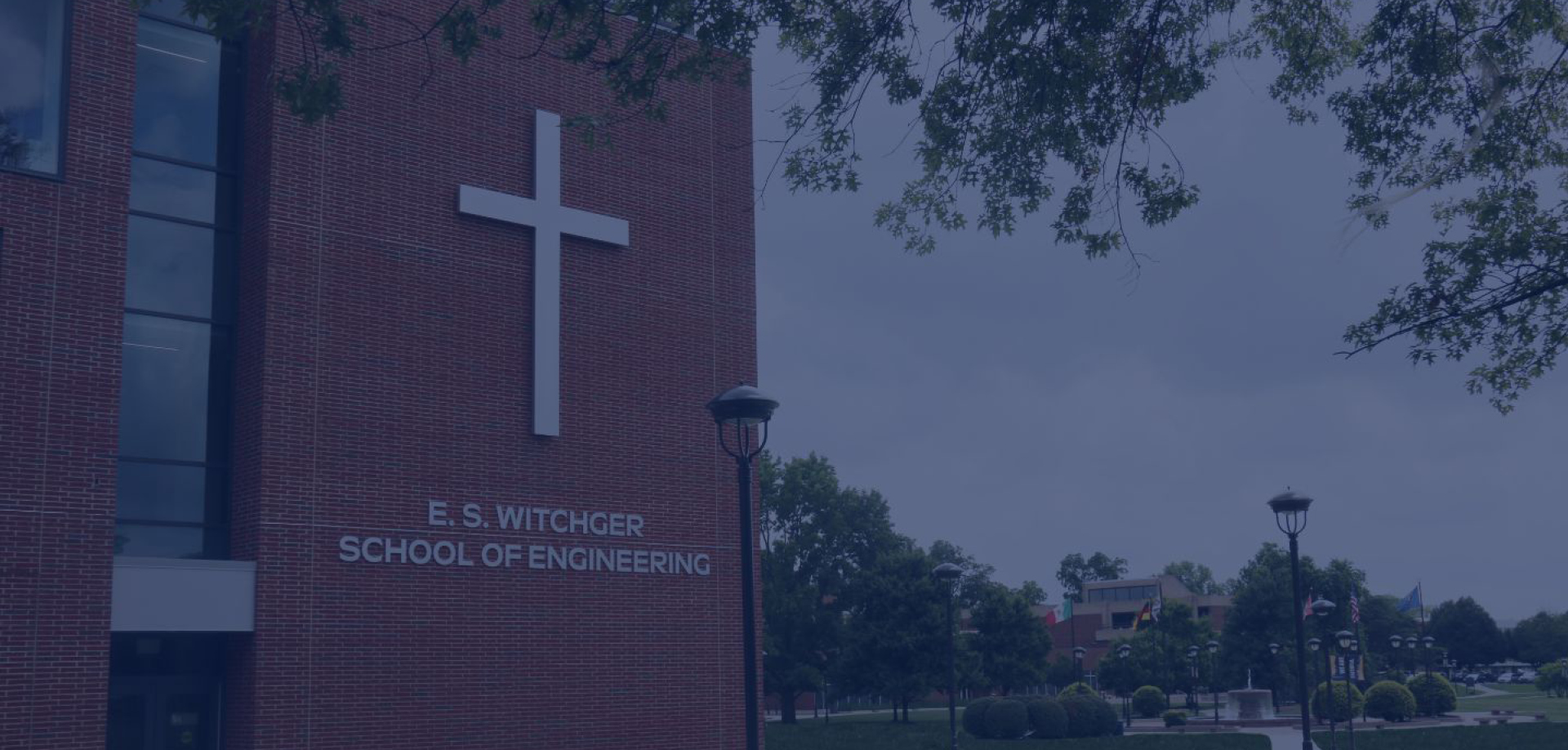 Brick campus building with a large white cross and the sign 'E. S. Witchger School of Engineering' on the wall.
